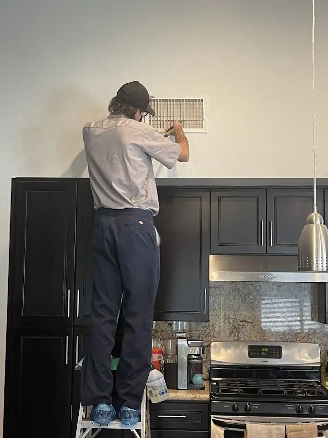 Technician inspecting an air vent during HVAC service in Clark